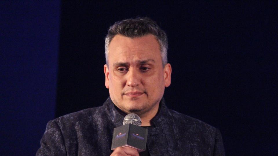 Joe Russo memegang mic dan menggunakan kemeja berwarna hitam.